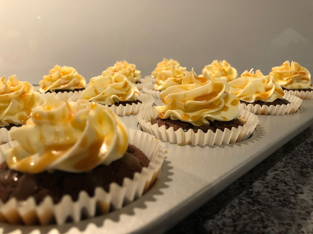 Tray of iced cupcakes with caramel sauce